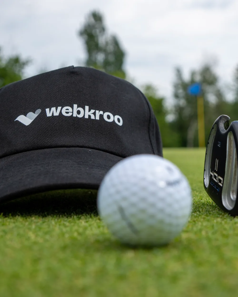 A WebKroo cap, a golf ball and a putter on the green at the tournament.