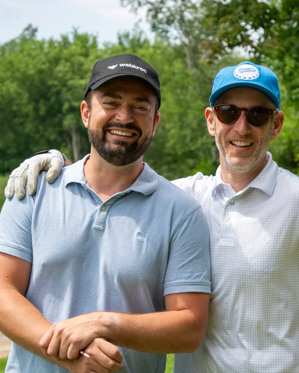 Two golfers with an arm around each other's shoulders on the course.